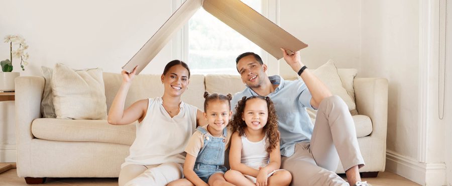 Vue d'une jeune famille tenant une boîte en carton pour former le toit d'une maison.