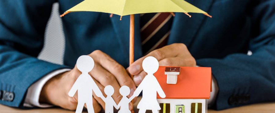 Mains d'homme avec famille en papier découpé, maquette de maison et parapluie